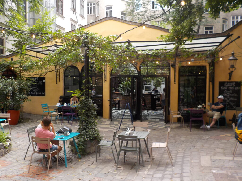 This picture shows an inviting outdoor cafe surrounded by vines and greenery.