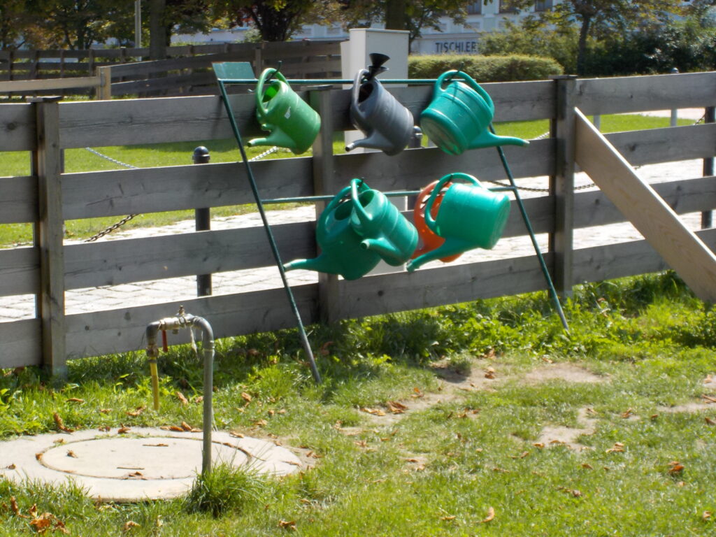 This picture shows watering cans hanging in a community garden