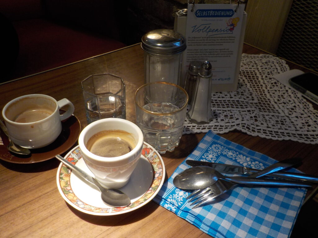 A Sunday morning in a café. The image shows a coffee cup and flatware on a table.