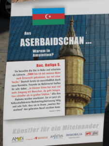 "Menschen aus aller Welt daheim in Amstetten" poster: full text of poster is included as the reading text for Azerbaijan below. An image of the Azerbaijan flag and a mosques minaret.