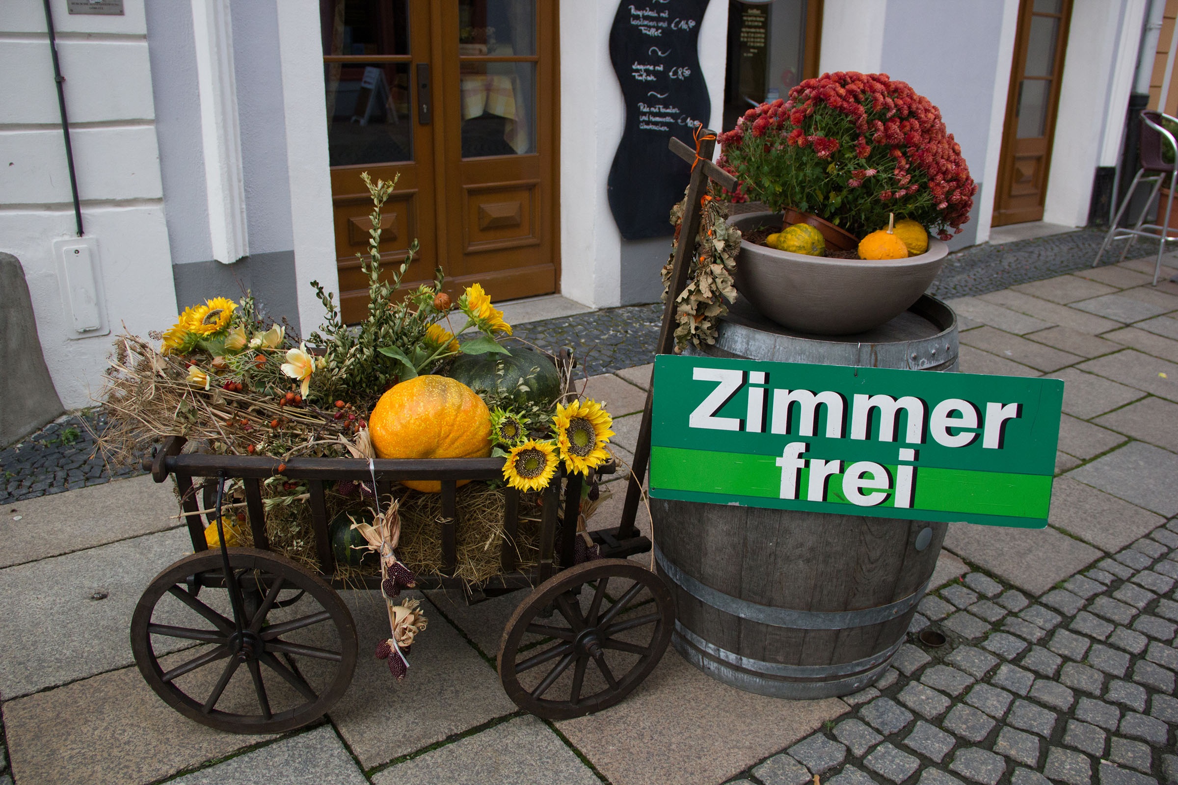 Storefront decoration of a cart full of plants with a sign that reads "Zimmer frei"